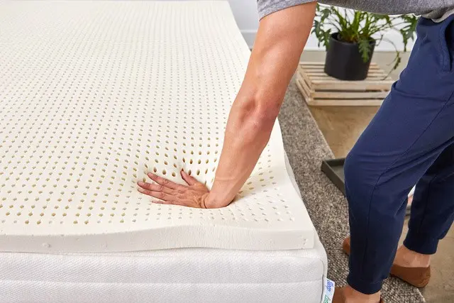 a hand is pressing the pure green latex mattress firmly to check its firmness
